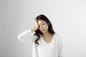 女性が頭を押さえている