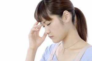 頭を押さえている女性